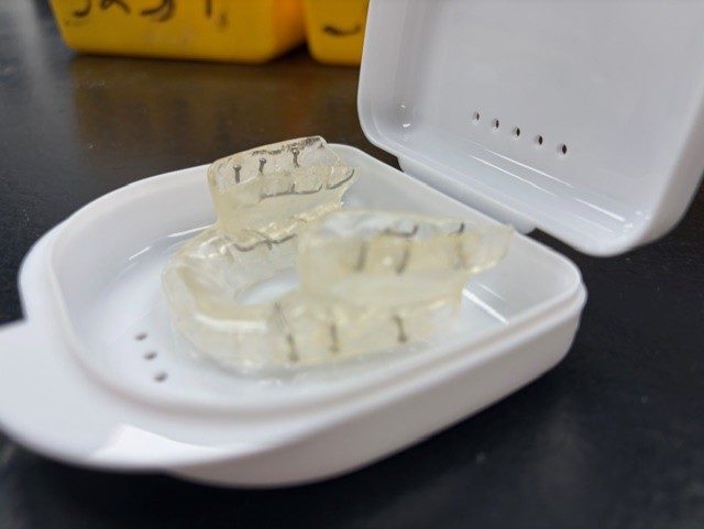 Clear orthodontic retainers in a storage case.